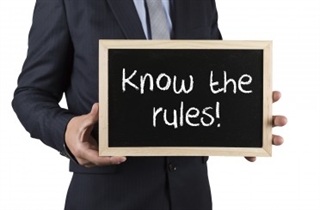 man holding sign with "know the rules" written